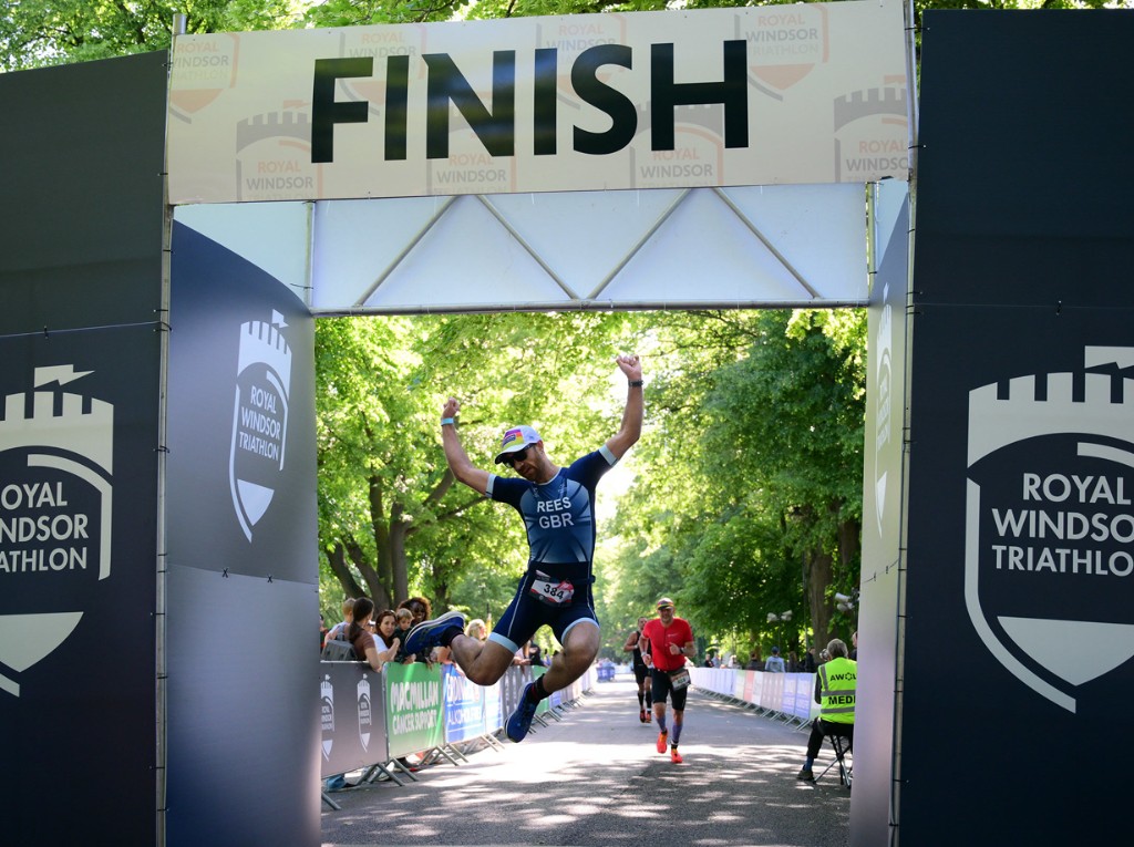 Athlete jumping under the Royal Windsor Triathlon finish banner